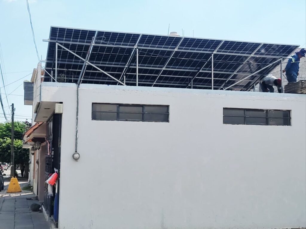 Technicians installing a rooftop photovoltaic solar panel system for a commercial property in Mexico.
